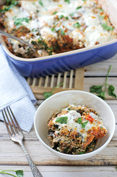 A serving of Baked Eggplant Casserole in a white bowl with the baking dish to the side.