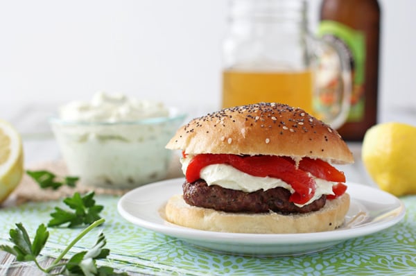 A Mediterranean Burger on a plate with a glass of beer.
