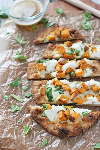 A sliced up Sweet Potato Brown Butter Flatbread on a wooden surface.