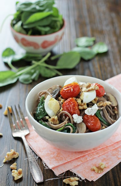 A white bowl filled with Soba Noodles with Tomatoes and a fork to the side.