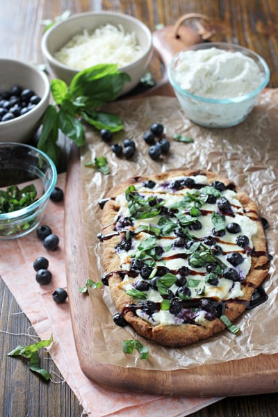 A Blueberry Flatbread on a wooden cutting board.