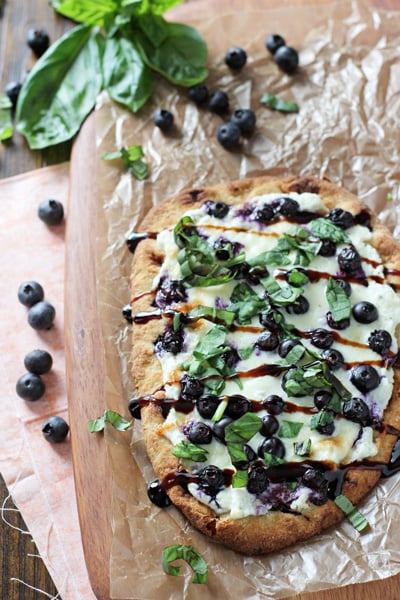 A Naan Pizza on a wooden cutting board.