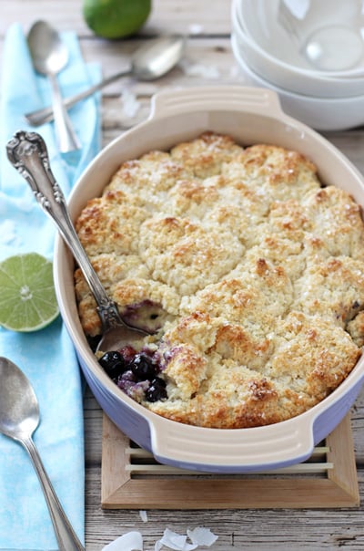 A purple baking dish filled with Blueberry Lime Coconut Cobbler.