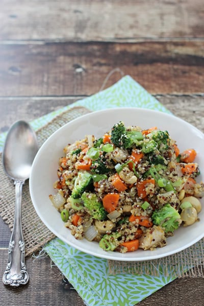 A white bowl filled with Quinoa Chicken and Broccoli with a serving spoon to the side.