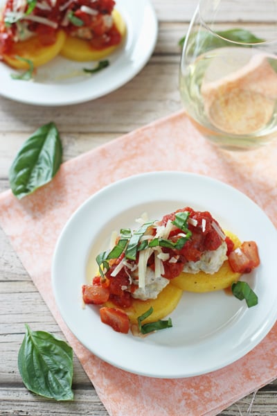 Two white plates with polenta cakes topped with Healthy Turkey Meatballs.