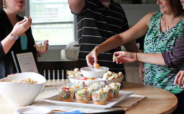 Several people enjoying appetizers around a kitchen table.