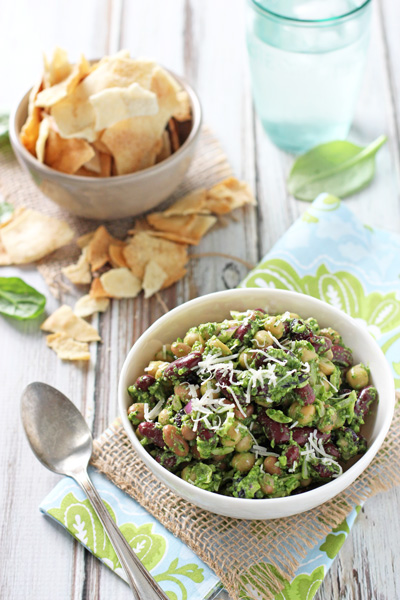 Two bowls filled with Pesto Bean Salad and pita chips.