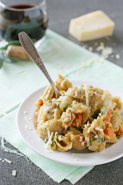 A white dish filled with Butternut Squash Pasta Sauce and shells with a fork in the dish.