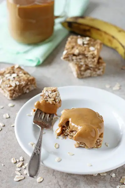 A Healthy Banana Bar on a white plate smeared with peanut butter.