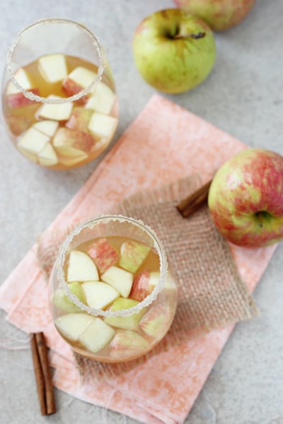 Two glasses of Apple Cinnamon Sangria with fresh apples to the side.