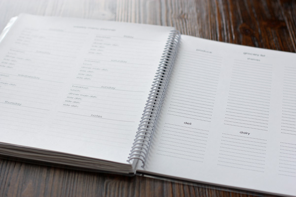 A meal planning notebook on a wooden table.