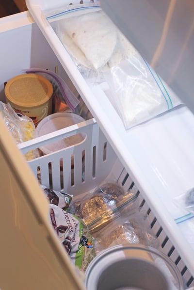 An open freezer drawer filled with groceries.