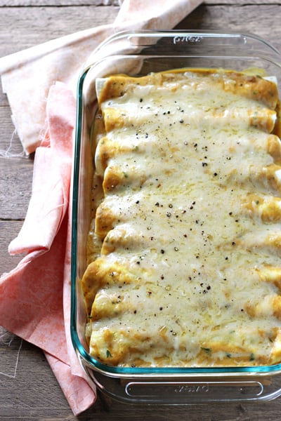 A glass baking dish filled with Butternut Squash Sausage Enchiladas.