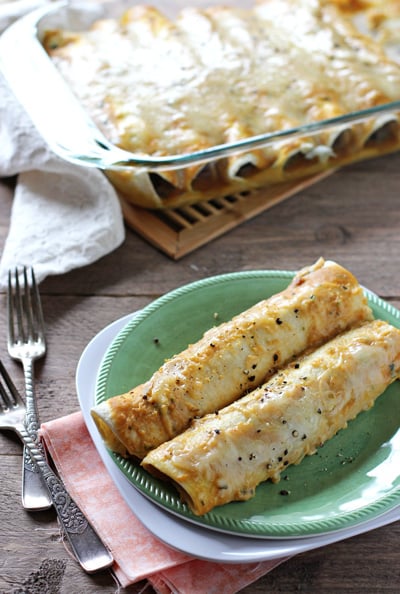 Two Fall Enchiladas on a green plate with the baking dish in the background.