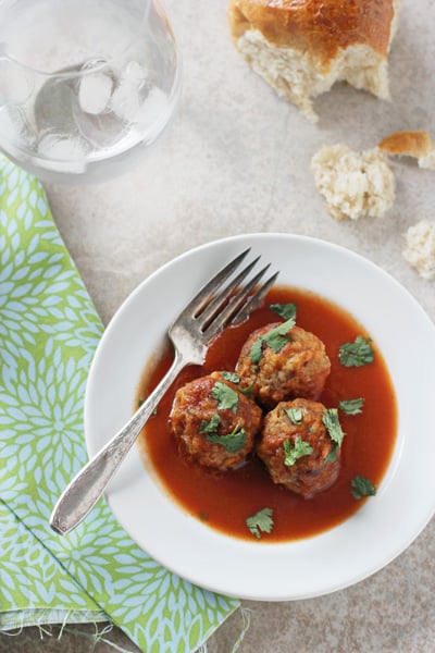 Three Crockpot Tex-Mex Meatballs on a white plate with a fork.