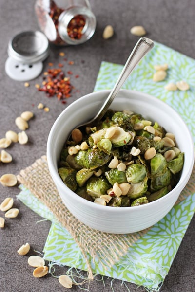 A white ramekin filled with Honey Roasted Brussels Sprouts with a spoon in the dish.