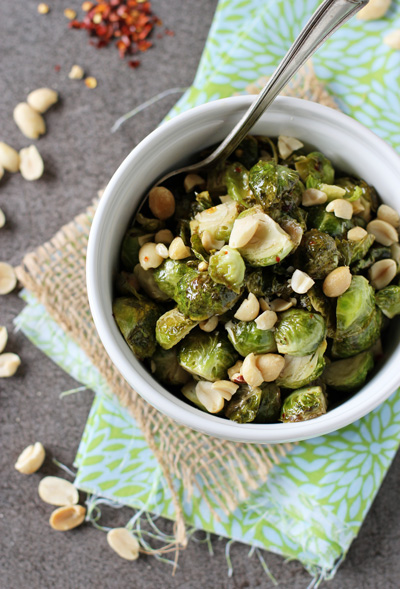 A white bowl filled with Honey Brussels Sprouts with a spoon in the dish.