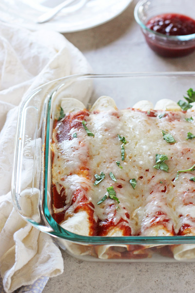 A glass baking dish filled with Thanksgiving Enchiladas with a napkin to the side.