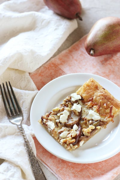 A white plate with a slice of Pear Goat Cheese Tart and a fork to the side.