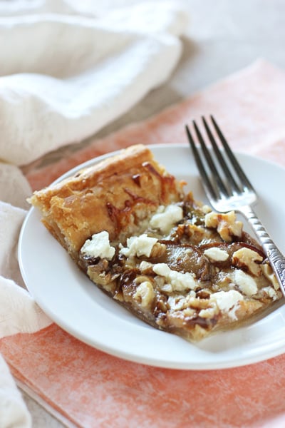 A slice of Pear Walnut Tart on a white plate with a fork.