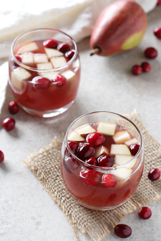 Two glasses of Holiday Sangria with fresh cranberries scattered around.
