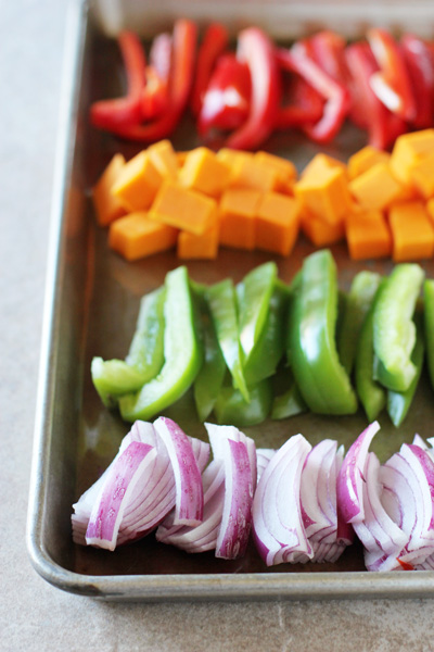 A baking sheet filled with sliced and chopped rainbow vegetables.