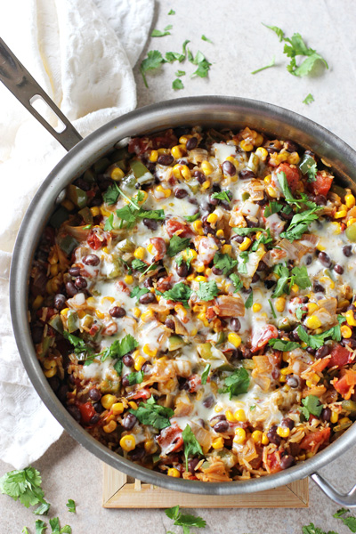 A stainless skillet filled with Skillet Mexican Brown Rice Casserole.