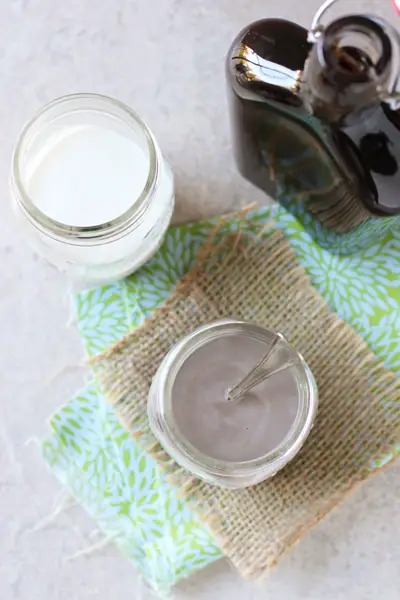 A glass of chocolate milk, plain milk and a jar of Homemade Chocolate Syrup.