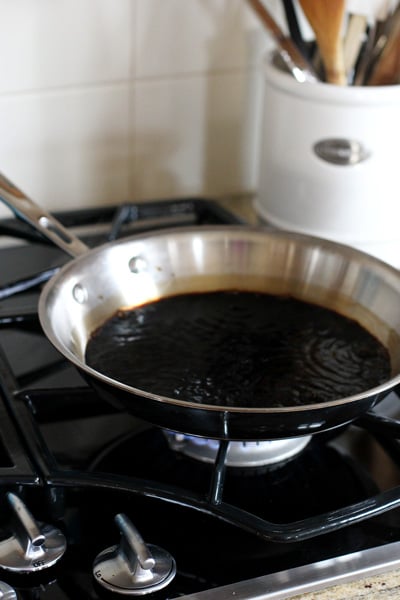 A skillet on a stovetop with simmering balsamic vinegar.