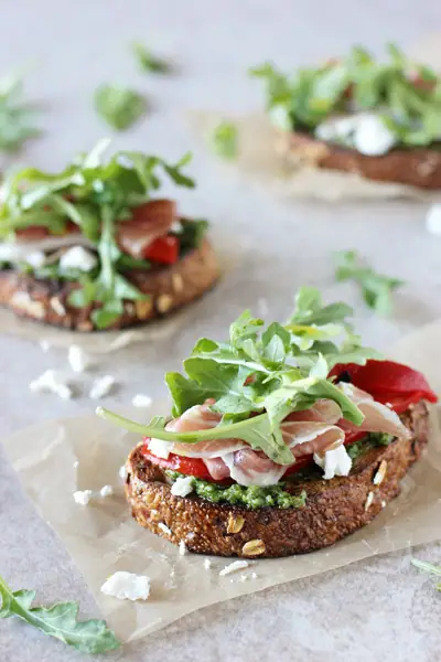 Three Pesto Open Faced Sandwiches on parchment paper.