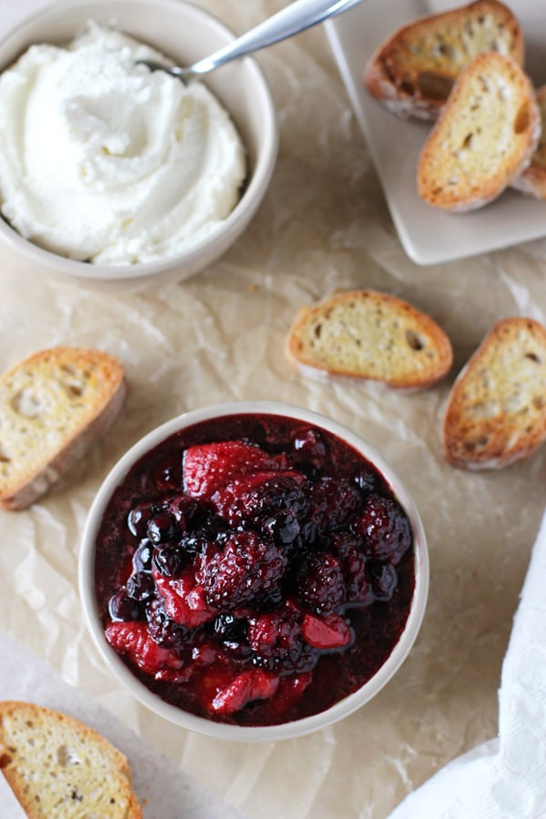 A bowl with roasted berries and another with ricotta. 