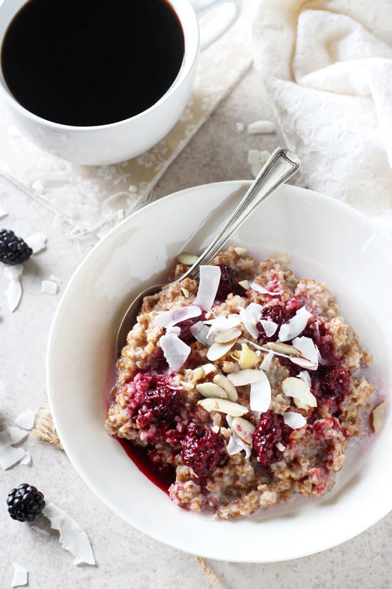 A white dish filled with a Bulgur Breakfast Bowl and a cup of coffee to the side.