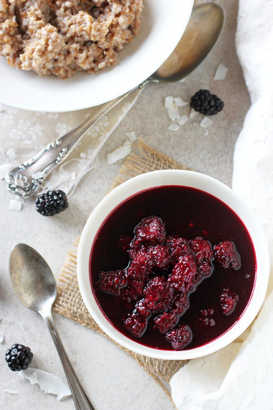 Two white dishes filled with blackberry sauce and bulgur oatmeal.
