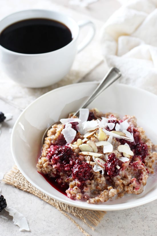 A white dish filled with Coconut Bulgur oatmeal and a cup of coffee in the background.