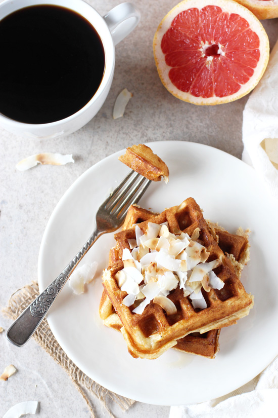 Two Grapefruit Waffles on a white plate with a bite taken out with a fork.