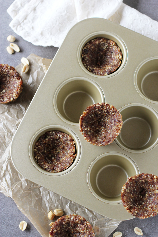 Raw vegan tart shells in a muffin tin.