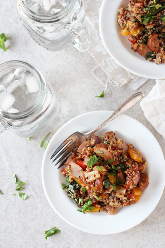 Two white plates filled with Cajun Quinoa and two water glasses to the side.