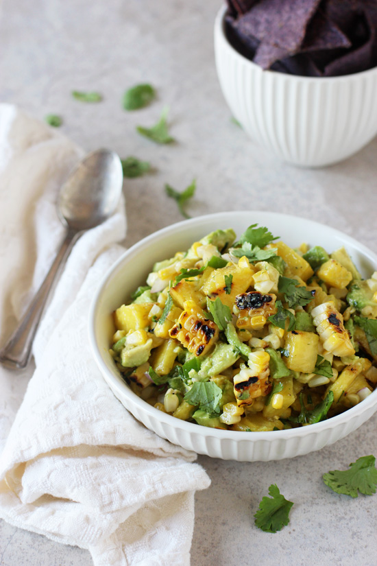 A white bowl filled with Pineapple Corn Salsa and chips in the background.