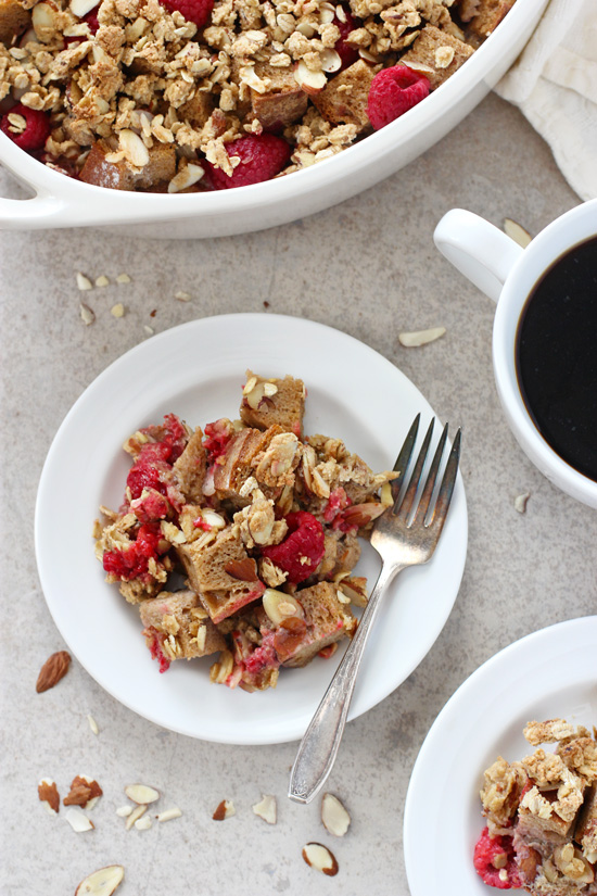 Two white plates filled with Almond Baked French Toast with the baking dish to the side.