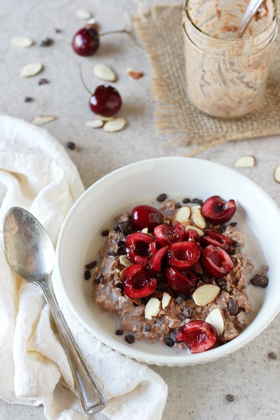 A white bowl filled with Chocolate Cherry Overnight Oats with a spoon to the side.