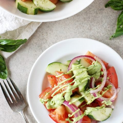 Recipe for quick and easy cucumber tomato salad. With fresh tomatoes, cucumbers and a creamy green goddess dressing lightened up with greek yogurt and avocado!