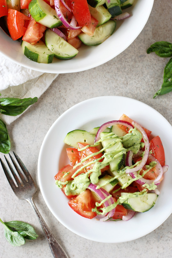 Two white dishes filled with Green Goddess Cucumber Tomato Salad.