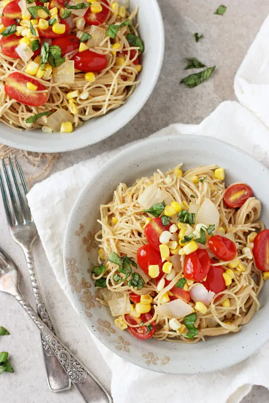 Two bowls filled with Tomato and Corn Angel Hair Pasta. 