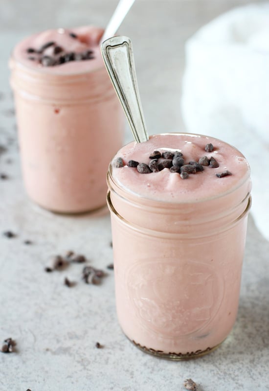 Two Watermelon Milkshakes on a white surface with spoons in the glasses.