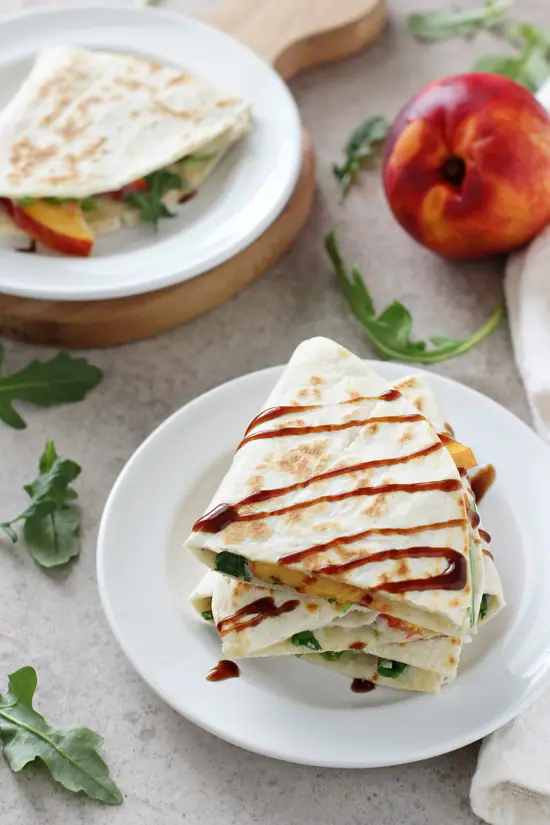 Several triangles of Peach and White Bean Quesadillas on white plates.