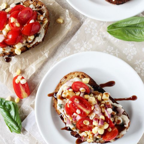 Recipe for quick and easy fresh corn and tomato open-faced sandwich. With a basil-packed white bean spread, a corn and tomato topping and balsamic glaze!
