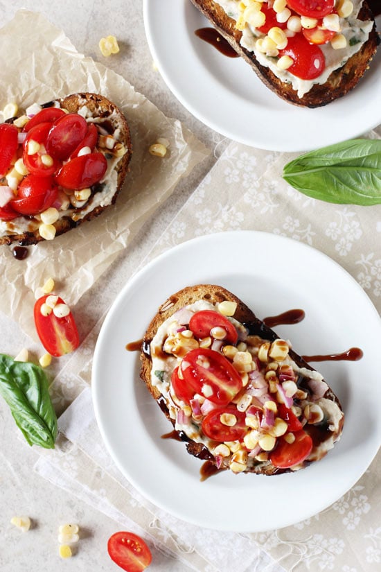 Three Tomato Corn Sandwiches on white plates and parchment paper.