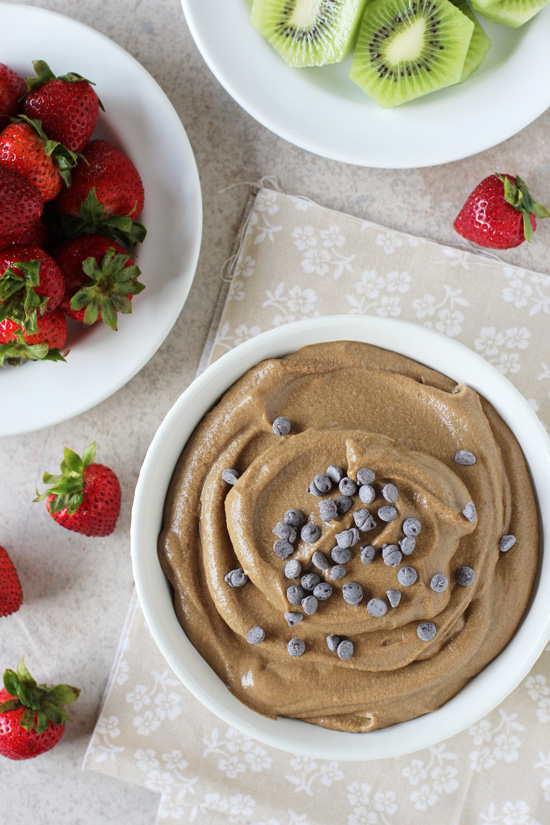 A white bowl filled with Healthy Chocolate Fruit Dip with fruit to the side.