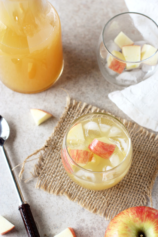 A glass filled with Ginger Apple Spritzer with an empty glass to the side.