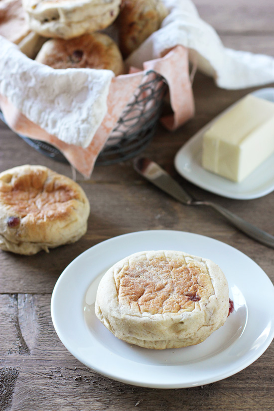 A Homemade Cranberry Walnut English Muffin on a plate with more in the background.